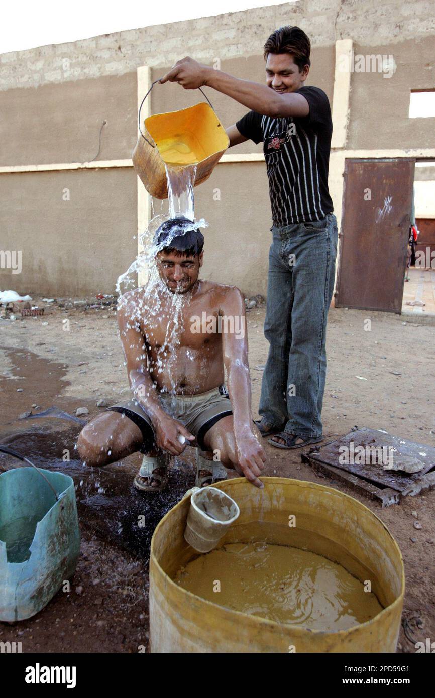 Gagandeep Singh, right, a migrant from India, pours water over a friend  washing himself in the town of Zouerate, Mauritania, Wednesday, April 19,  2006. There are no roads to this Sahara Desert