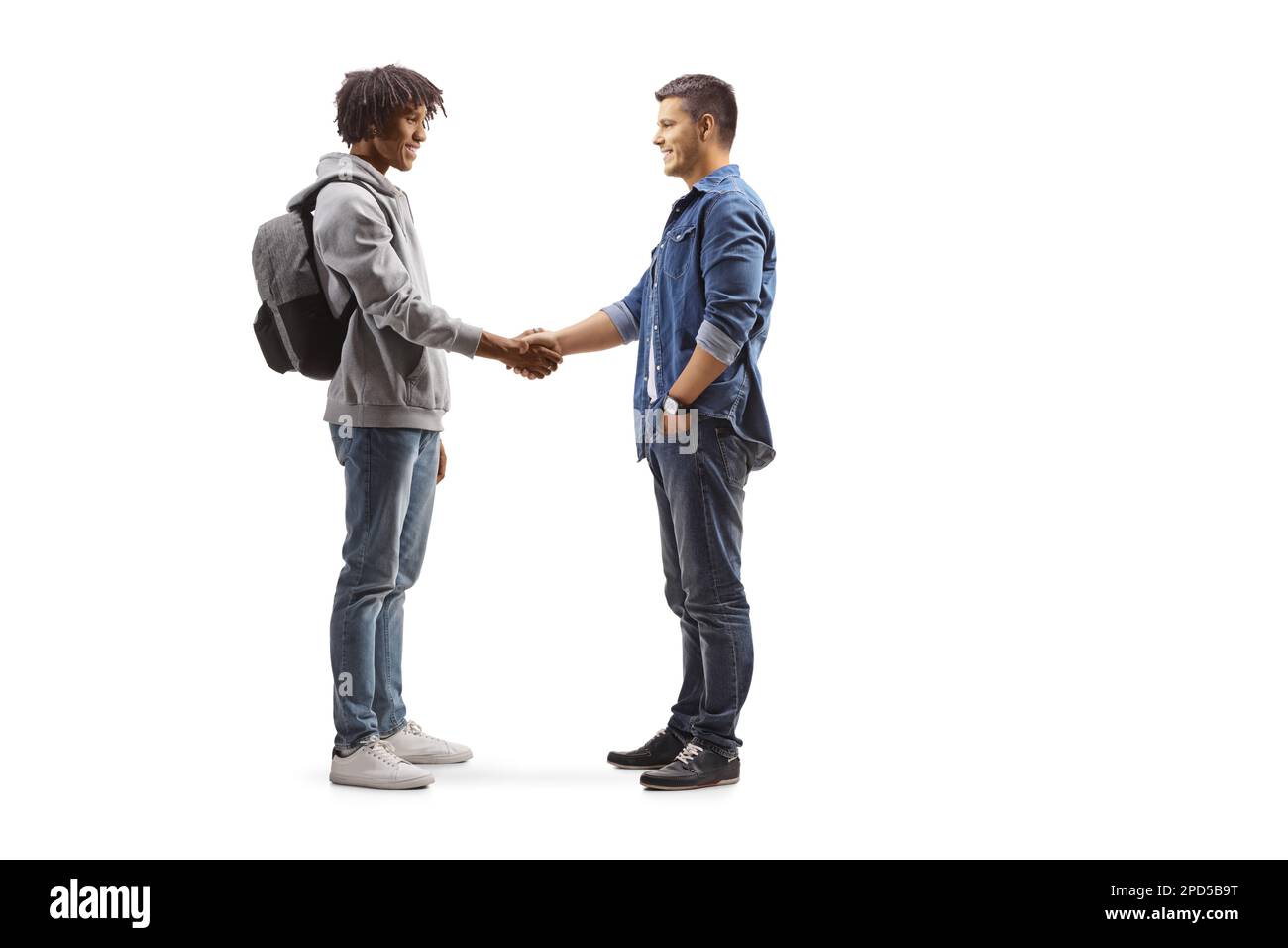 Full length profile shot of an african american male student and a caucasian man shaking hands isolated on white background Stock Photo
