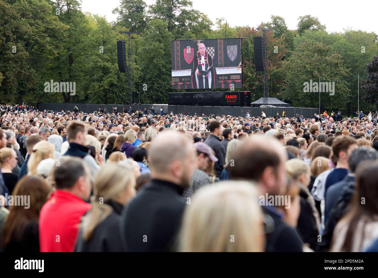 People watch the TV coverage of the late Queen Elizabeth II’s funeral day on a large screen in Hyde Park, London. Stock Photo