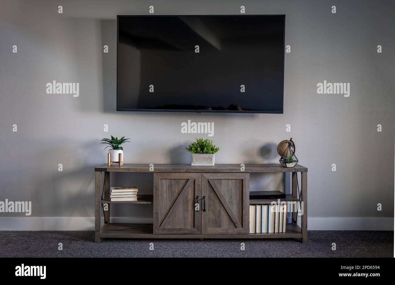 Large flatscreen television on grey wall with TV stand decorated with