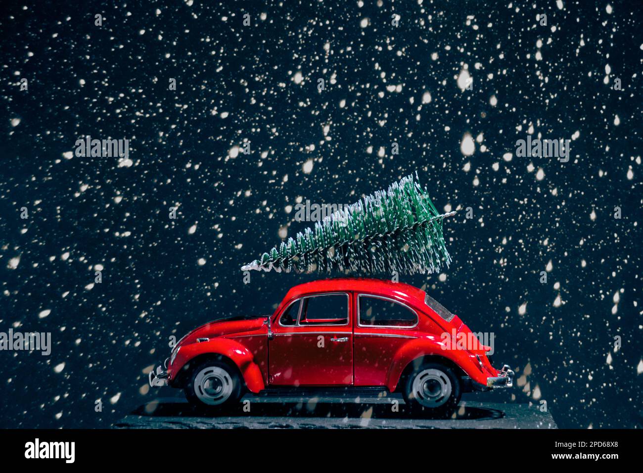 Red retro car with Christmas tree on roof during heavy snowfall Stock Photo