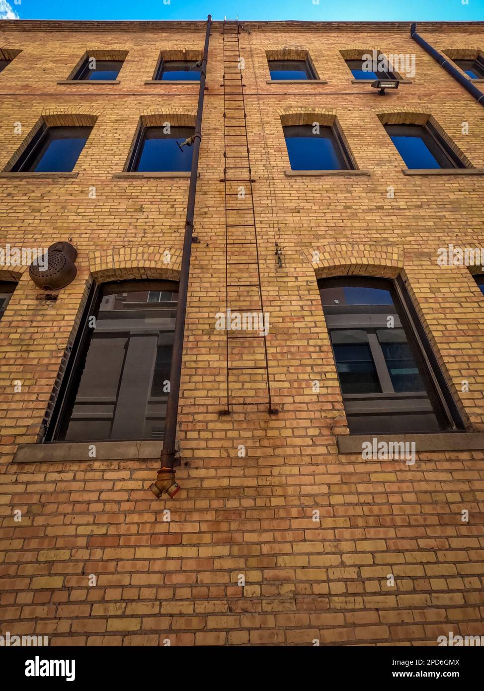 The exterior side of a four story brown brick building with a fire