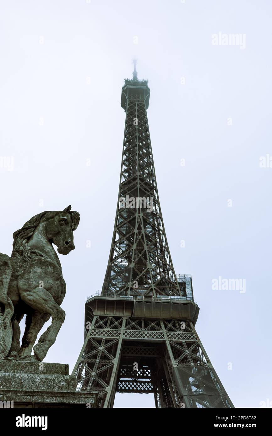 A black horse statue stands atop a ledge overlooking the iconic Eiffel Tower in Paris, France Stock Photo