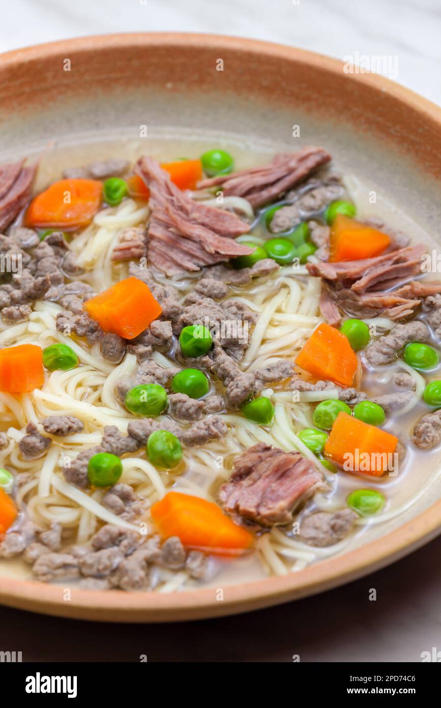 beef broth with green peas, carrot and small meatballs Stock Photo