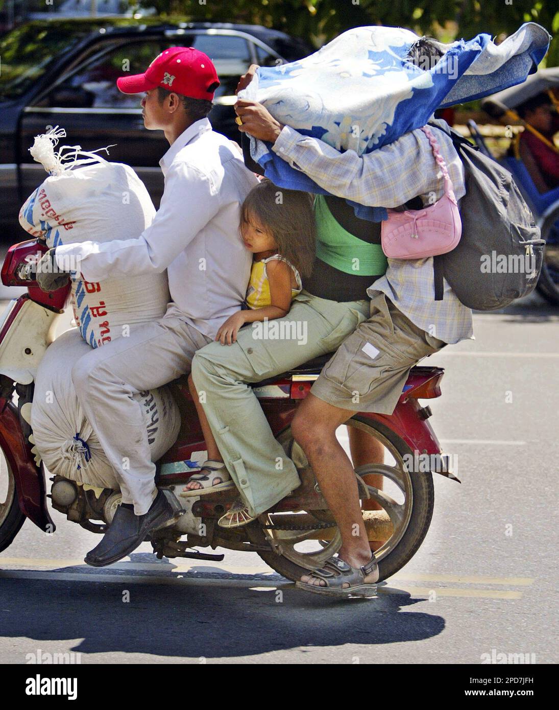 A Cambodian girl is sqeezed between a driver and a passenger of an  overloaded motorbike taxi in the capital Phnom Penh, Tuesday, April 4,  2006. Overloaded motorcycles and cars are a common