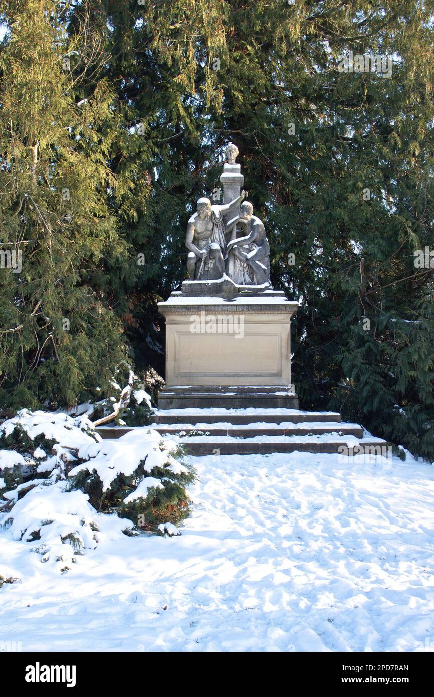 Karlsruhe, Germany - February 12, 2021: Statue in the trees in Karlsruhe Palace gardens on a winter day with snow on the ground in Germany. Stock Photo