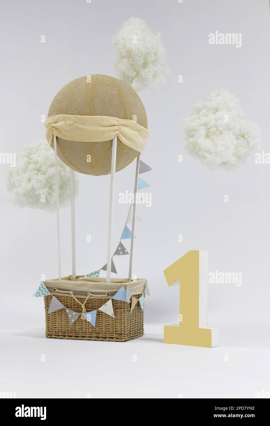 A decorative holiday balloon with a basket, tags and clouds installed in a photo studio and a big number one. Beautiful decor for festive photo shoots Stock Photo