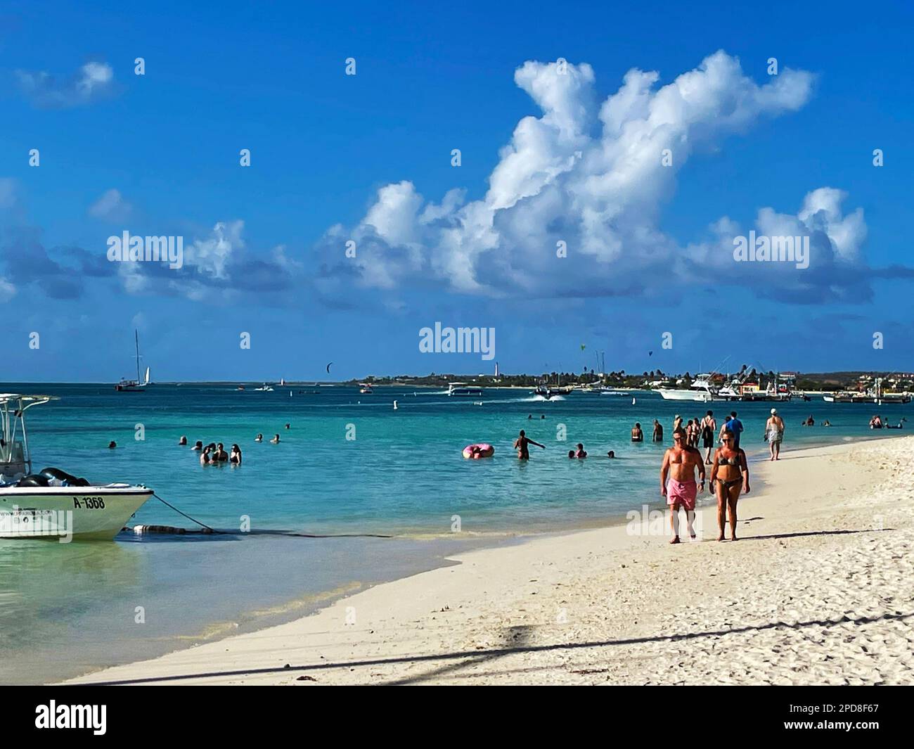Palm Beach, Noord, Aruba - March 10, 2022. People on the beach and in the water. Hotels, resorts and boats in the background. Stock Photo