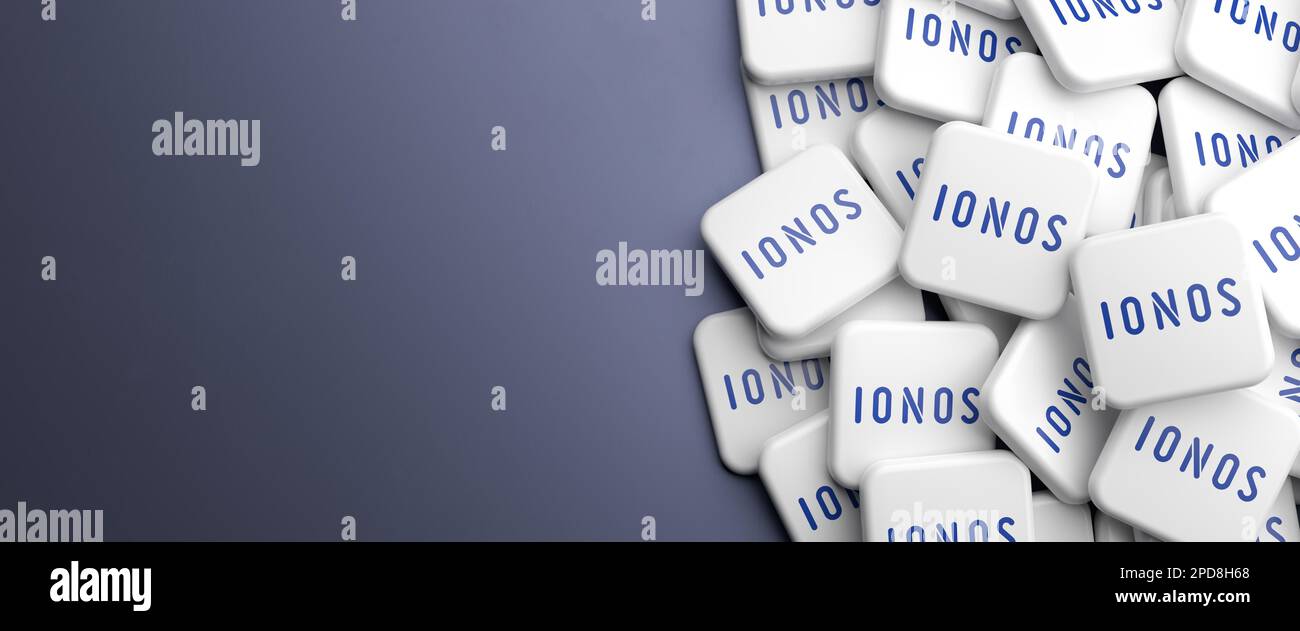 Logos of the web hosting company IONOS on a heap on a table. Copy space. Web banner format. Stock Photo