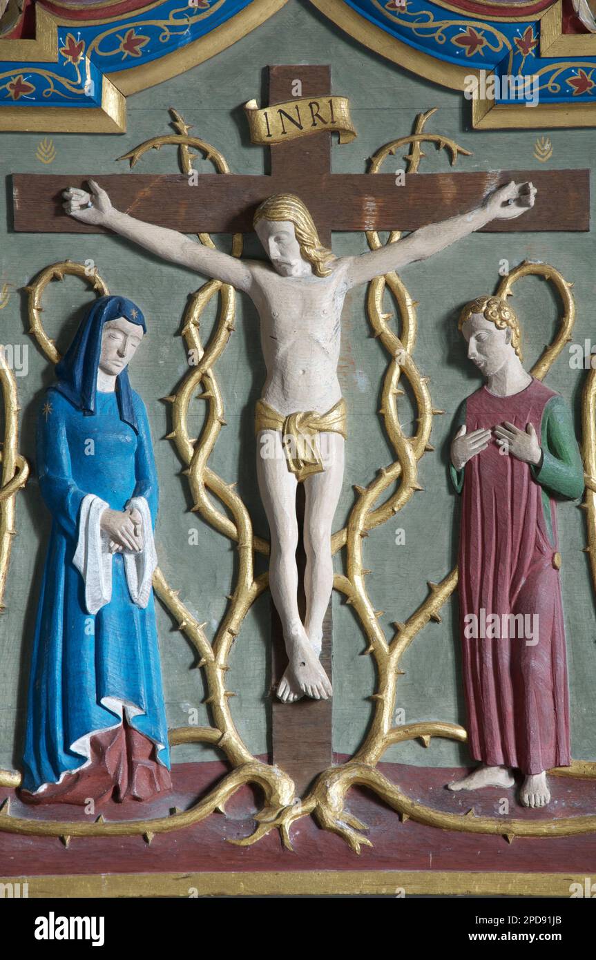 Carved and painted depiction of the crucifixion of Jesus Christ on a reredos behind the altar of St Laurence’s Church, Affpuddle, Dorset, England, UK. Stock Photo