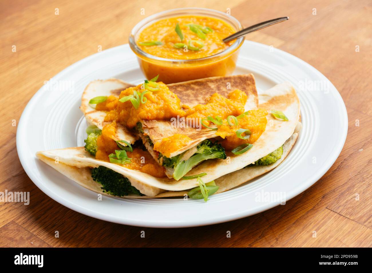 Plate with vegan broccoli quesadillas, served with an apricot-carrot sauce. Stock Photo