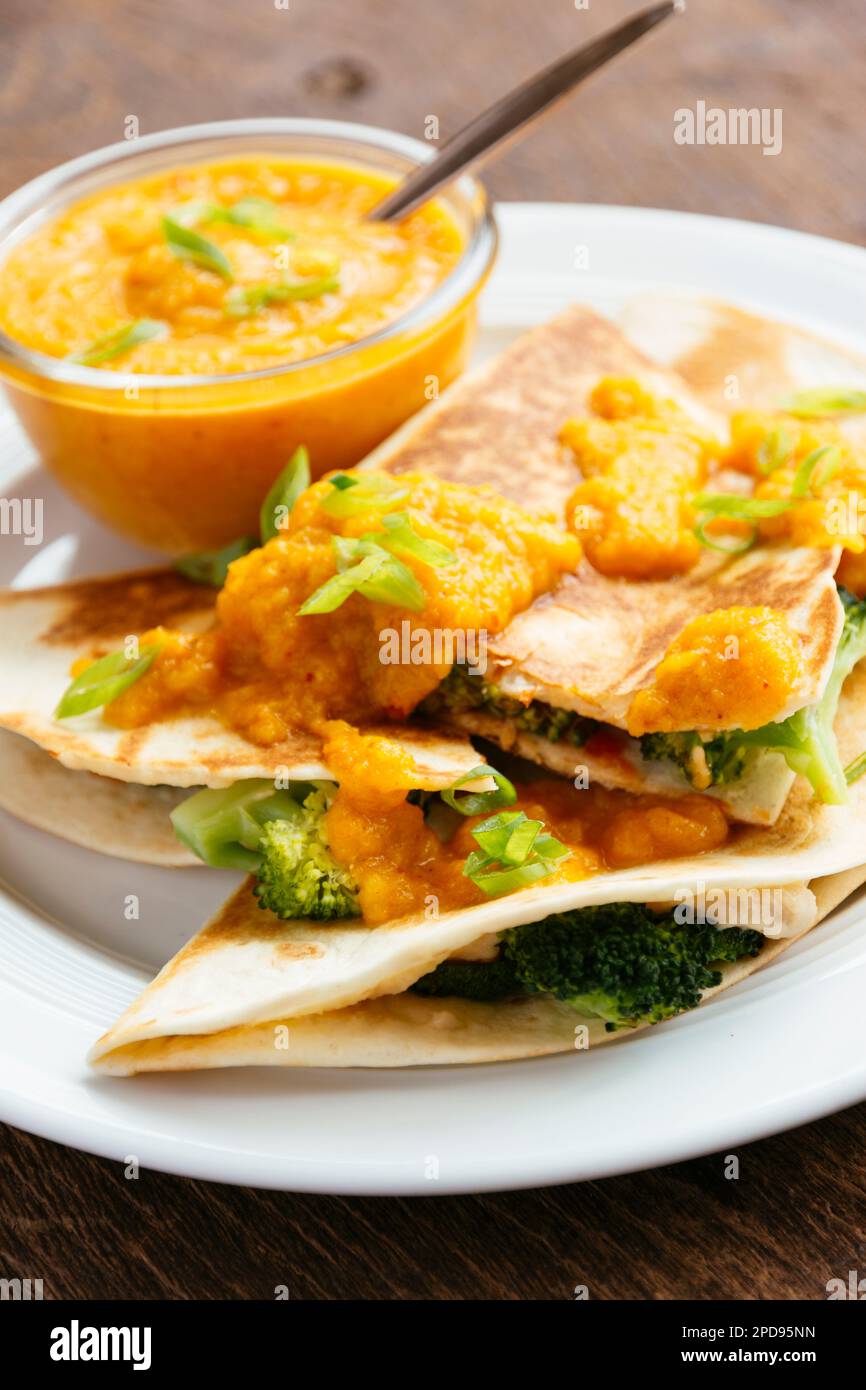 Plate with vegan broccoli quesadillas, served with an apricot-carrot sauce. Stock Photo
