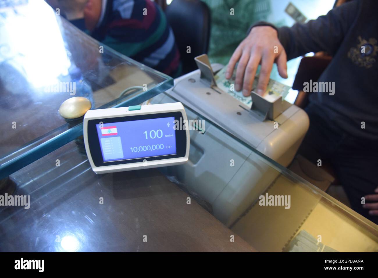 Tripoli, Lebanon. 14th Mar, 2023. A teller uses a bill counter to count Lebanese currency at a