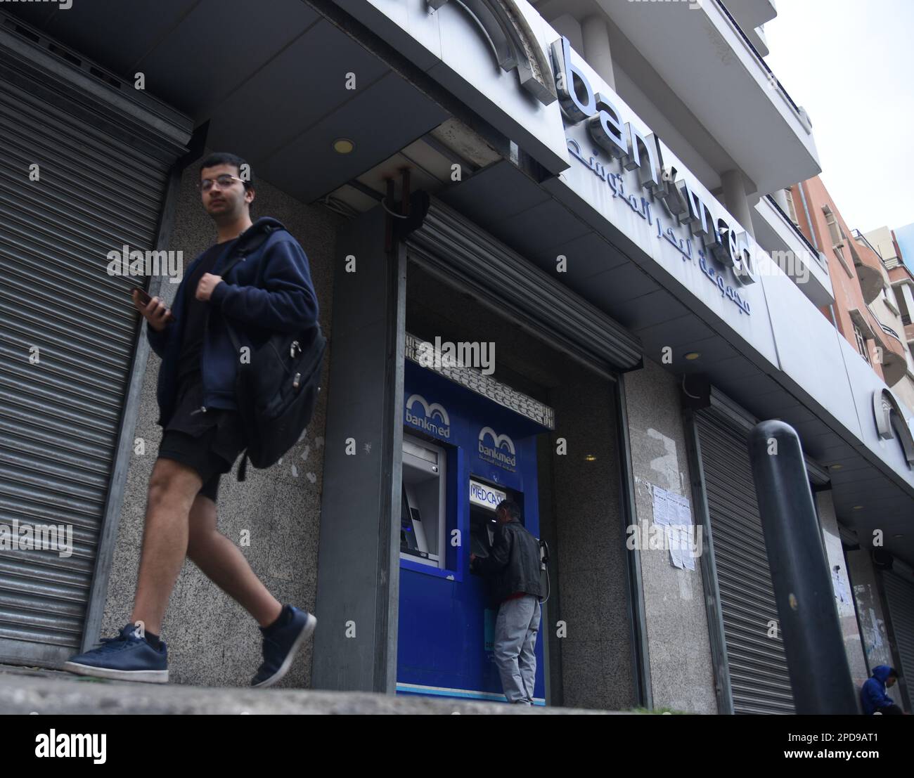Tripoli, Lebanon. 14th Mar, 2023. A man walks past a closed bank in Tripoli, Lebanon, on March