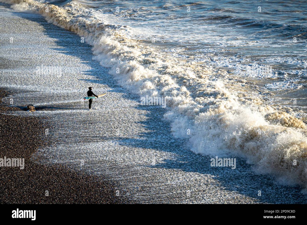 Birling Gap, West Sussex, UK. 14th Mar, 2023. Man versus nature as a lone surfer braves choppy seas and surf in late afternoon sun. The weather on the south coast was sunny and breezy allowing some invigorating winter surfing. Credit: Julian Eales/Alamy Live News Stock Photo