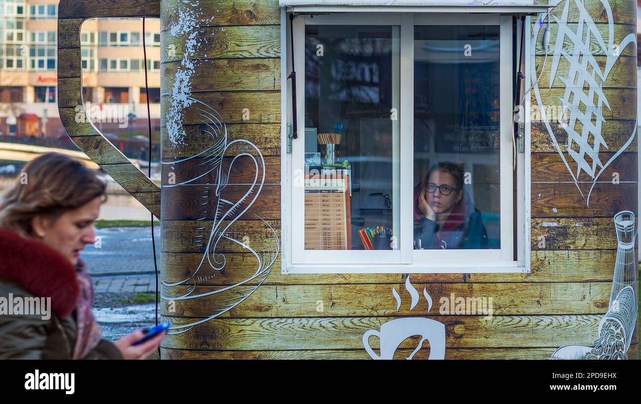 Minsk, Belarus - December 15, 2017: A sad young girl saleswoman in a street store looks out the window Stock Photo