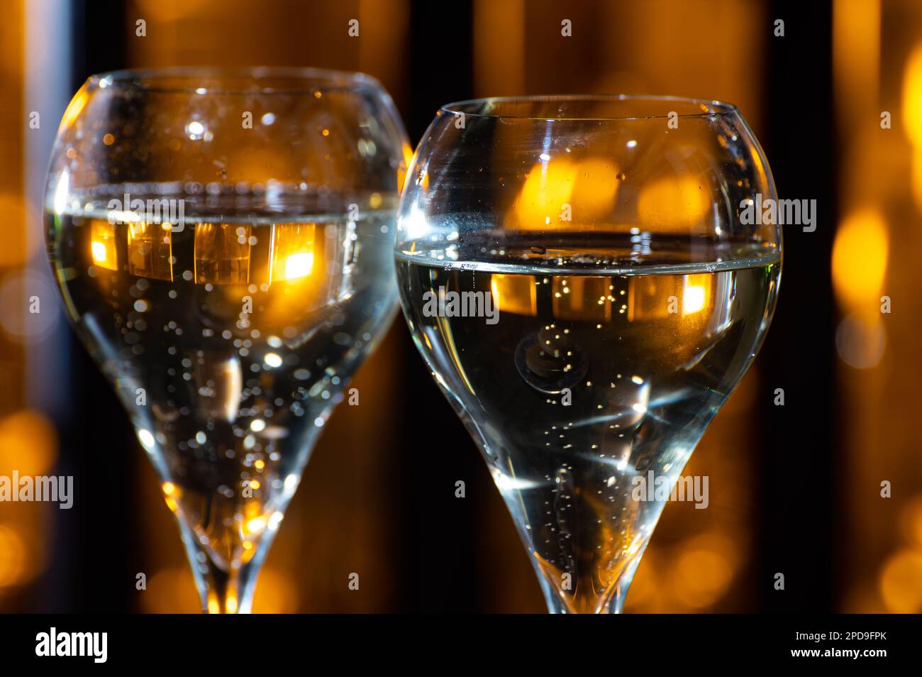 Glasses of brut champagne bubbles wine in tulip glass on evening bar lights background Stock