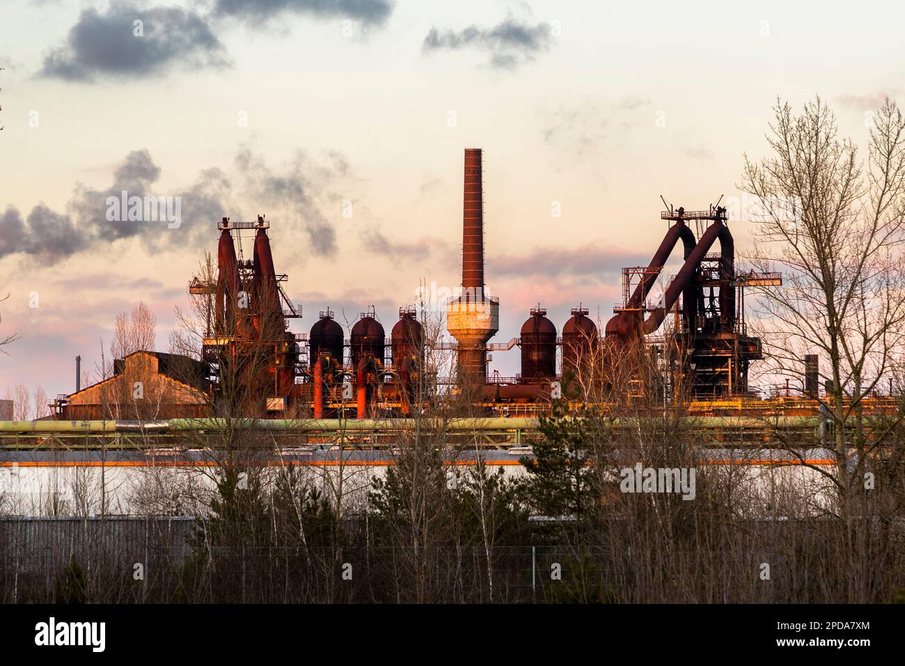 Ironworks in Eisenhüttenstadt (formerly Stalinstadt). The planned city has no church spires. The blast furnace is one of the tallest structures. As a central place of work, visual axes and main streets were aligned to the steel mill during planning in the early 1950s. The former EKO (Eisenhütten Kombinat Ost) steel factory of ArcelorMittal in Eisenhüttenstadt, Germany Stock Photo