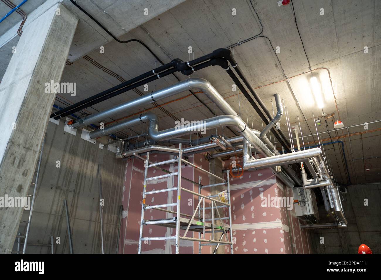 Heating and cooling System of the building. New pipe installation, mounted under the ceiling near plasterboard wall. Stock Photo