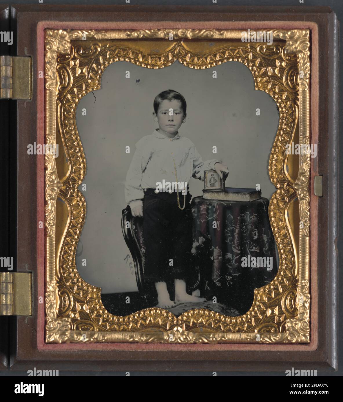Unidentified boy holding cased photograph of soldier in Confederate uniform atop a Bible / Rees