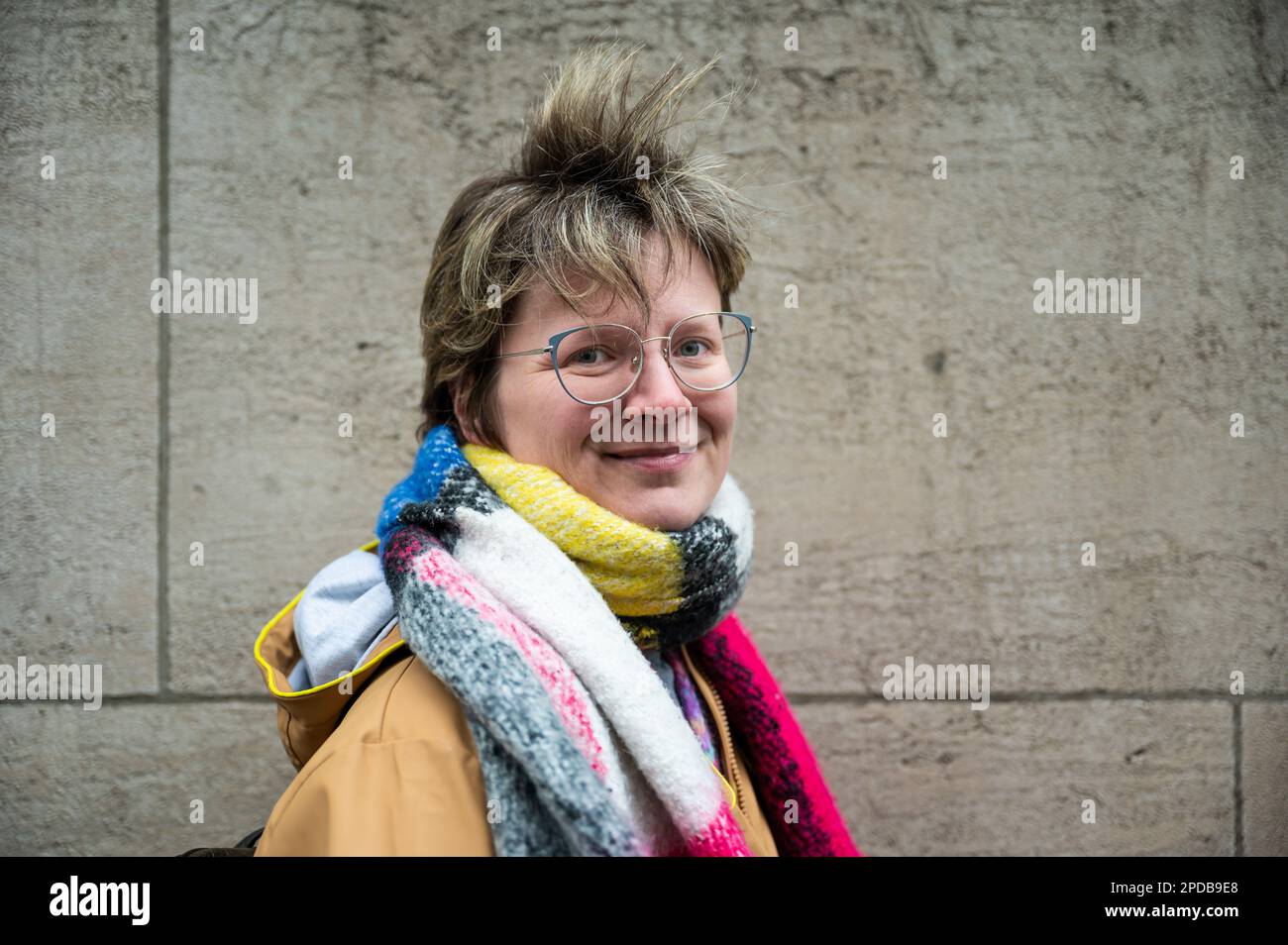 Portrait of a happy 36 year old white woman in a colorful scarf against a wall, Brussels, Belgium Stock Photo