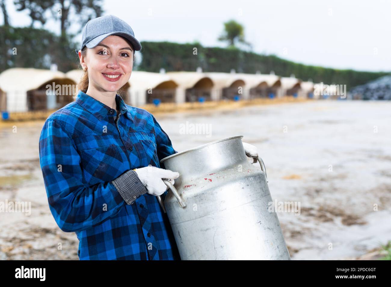 Female dairy farm owner standing in backyard wih milk can Stock Photo