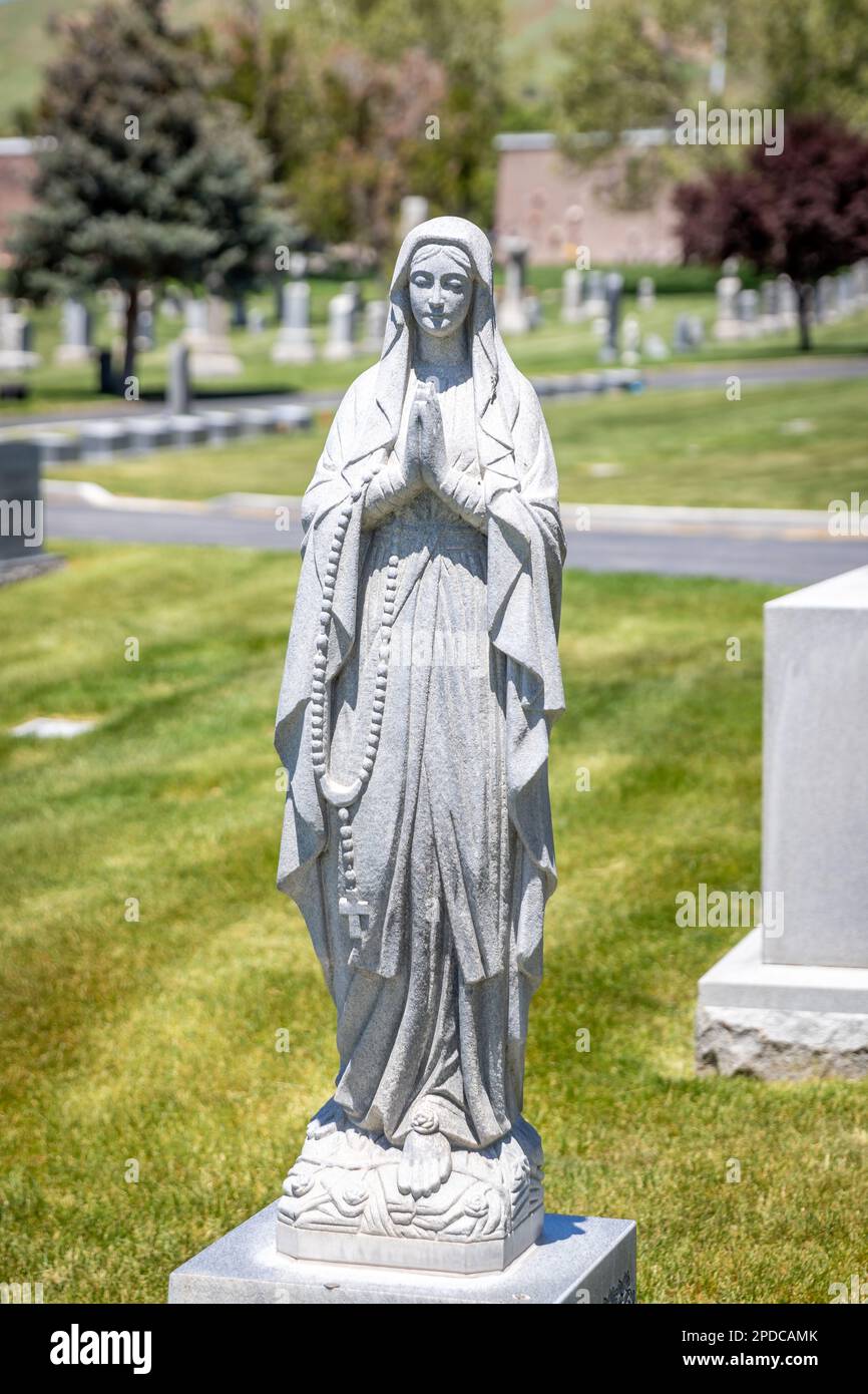 Granite stone Virgin Mary statue on the top of a headstone at the