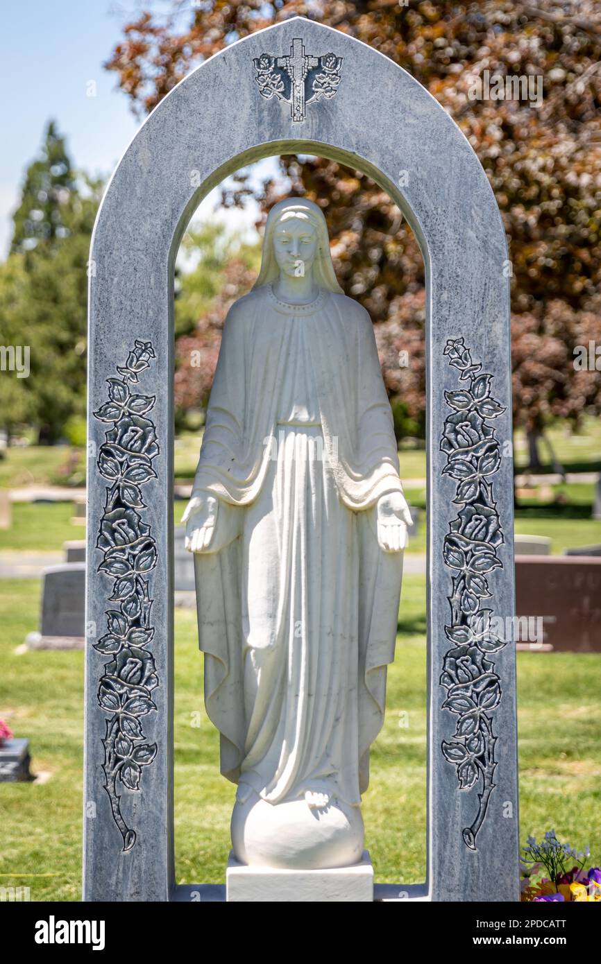 Granite stone Virgin Mary statue on a decorative Catholic headstone at