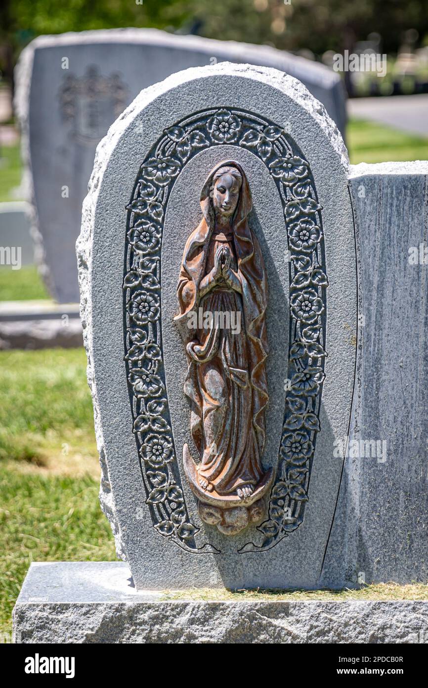 Granite headstone with a metal Virgin Mary mounted to the face of the