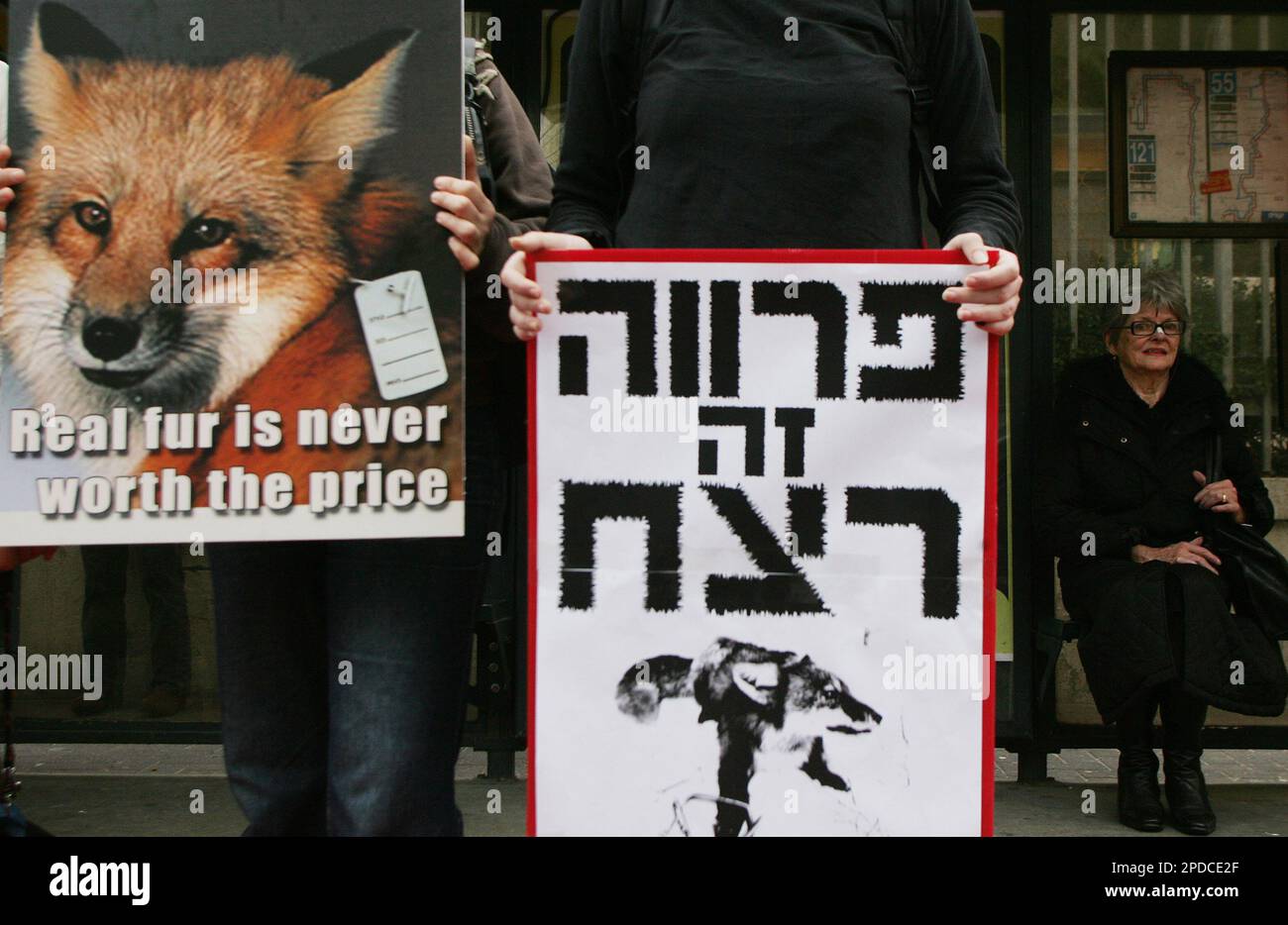 A woman waits for the bus as Israeli members of the International Anti-fur  Coalition protest outside of the Chinese Embassy in Tel Aviv Monday Feb. 13,  2006. The demonstration was part of