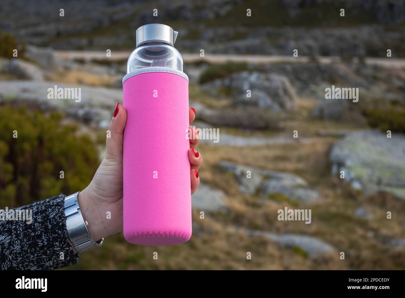 Refreshing hydration with a touch of sweetness: Glass water bottle with pink sleeve Stock Photo
