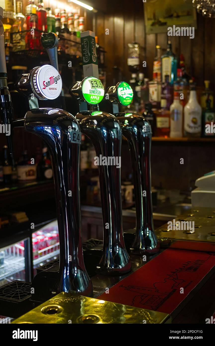 Beer brands displayed on the beer pumps behind the pub bar Stock Photo