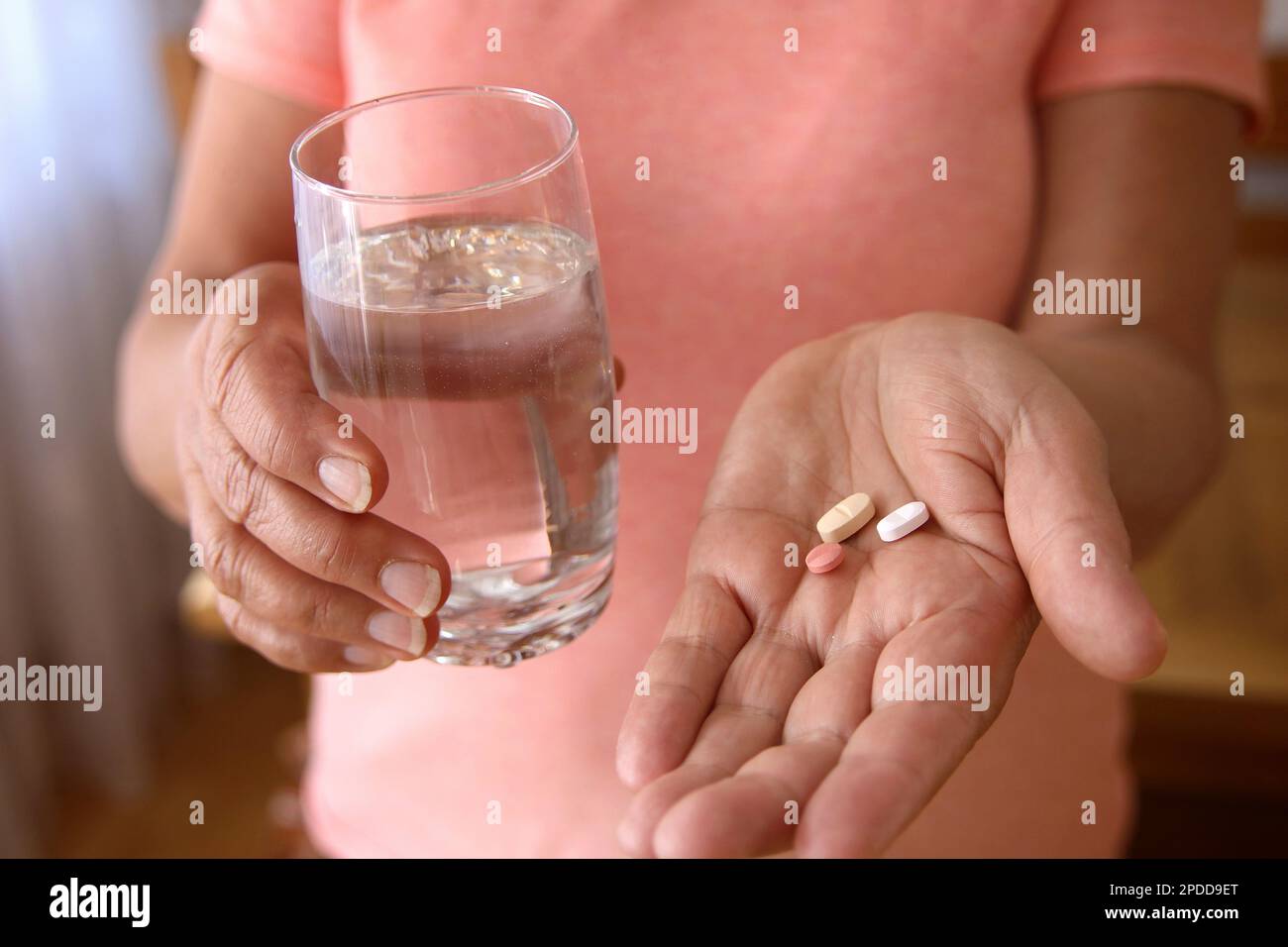 taking pills, woman holding pills and glass of water in her hands Stock Photo