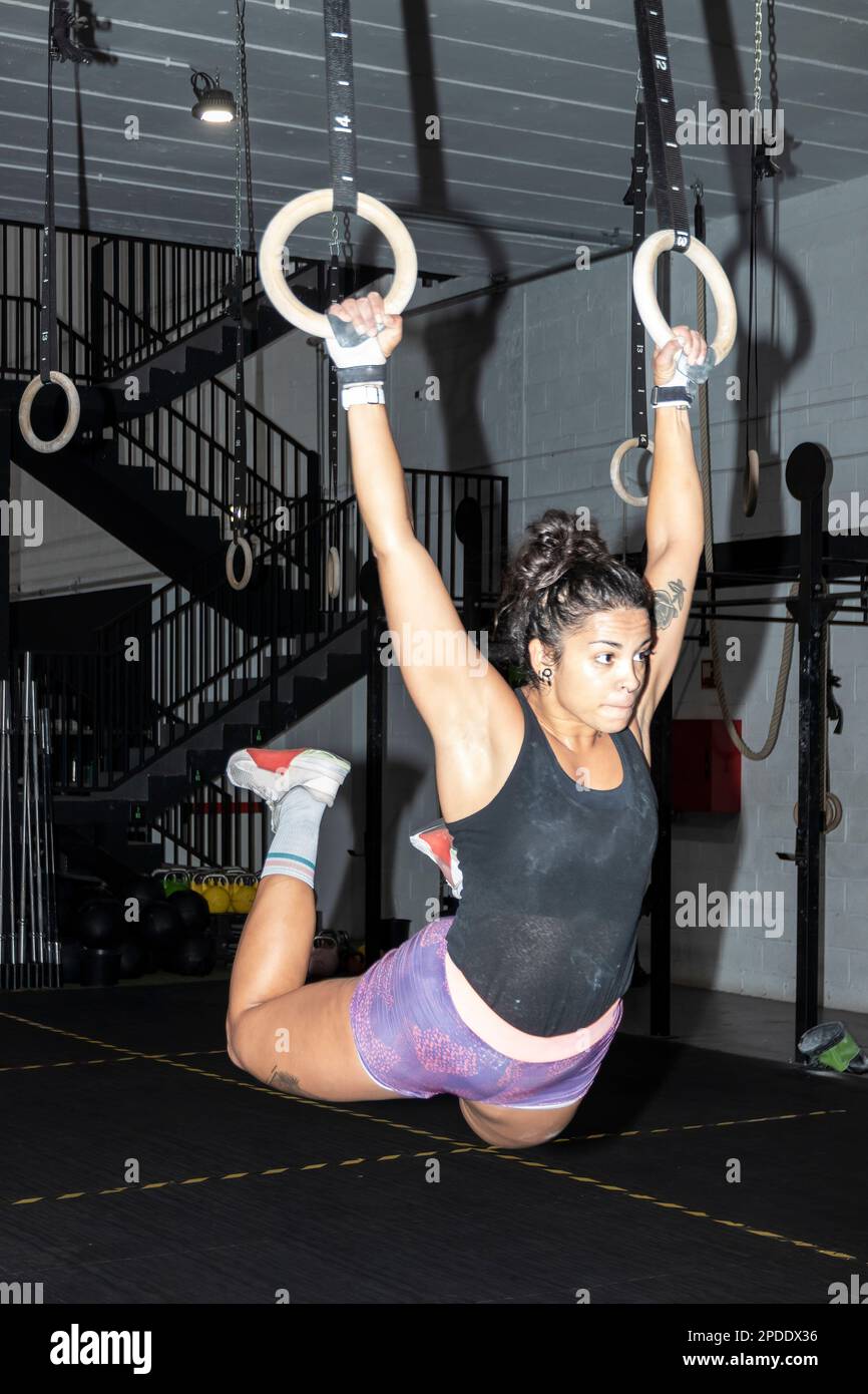 latin woman doing muscleups on gymnastic rings at the gym. Strong