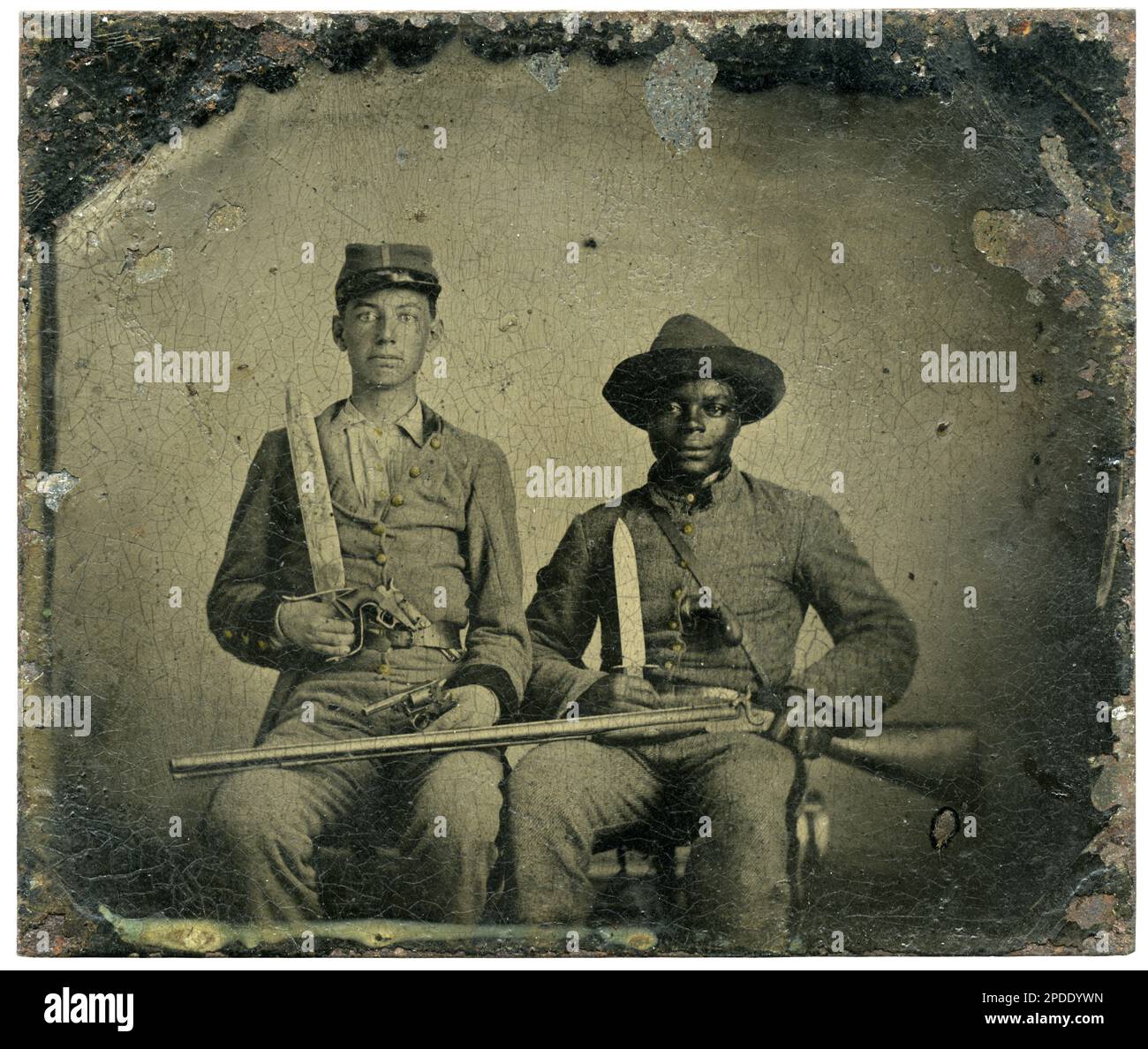 Sergeant A.M. Chandler of Co. F, 44th Mississippi Infantry Regiment, and Silas Chandler, family slave, with Bowie knives, revolvers, pepper-box, shotgun, and canteen. Liljenquist Family Collection of Civil War Photographs , FAmbrotype/Tintype photograph filing series , pp/liljconfed. Chandler, A. M, (Andrew Martin), 1844-1920, Chandler, Silas, 1837-1919, Confederate States of America, Army, Mississippi Infantry Regiment, 44th, People, 1860-1870, African Americans, 1860-1870, Slaves, 1860-1870, Soldiers, Confederate, 1860-1870, Military uniforms, Confederate, 1860-1870. Stock Photo