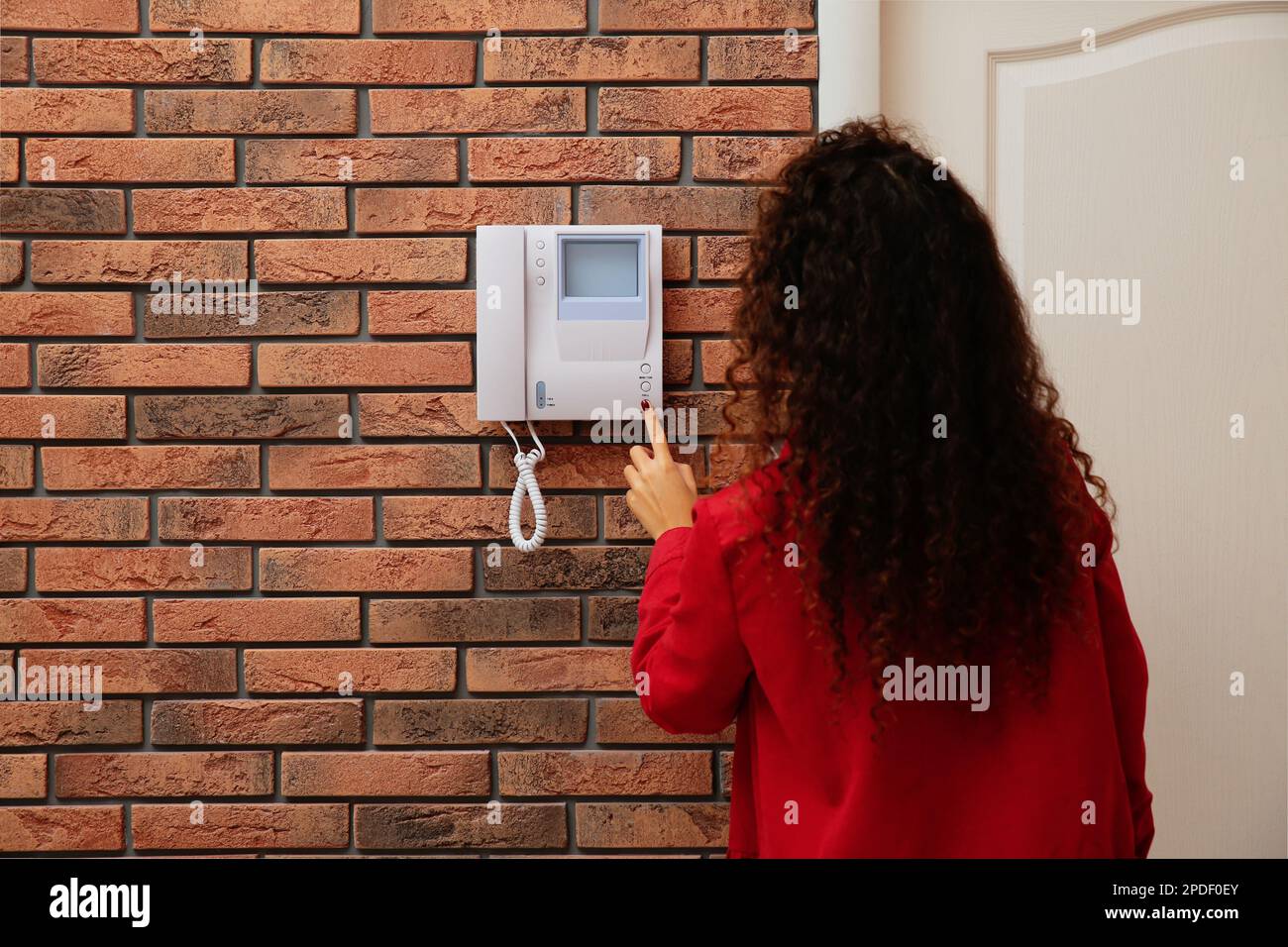 African-American woman pressing button on intercom panel indoors, back ...