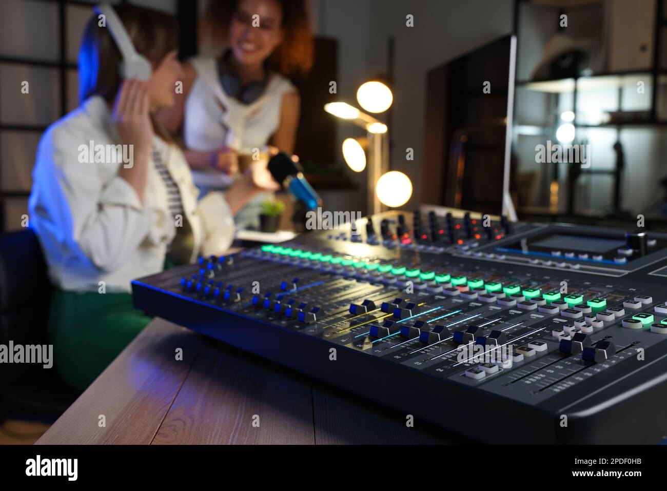 Women working in modern radio studio, focus on professional mixing console Stock Photo