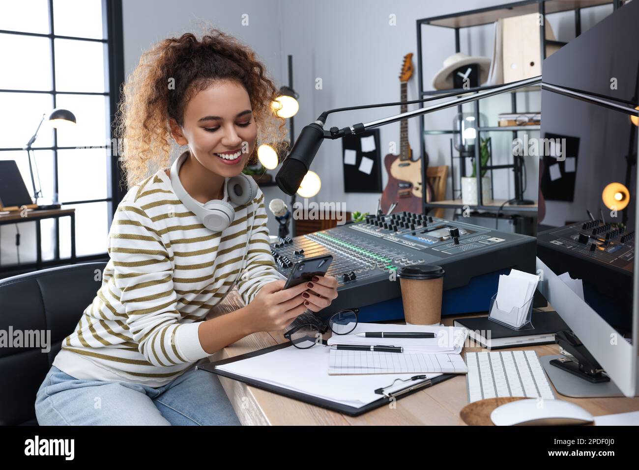 African American woman with smartphone working as radio host in modern ...