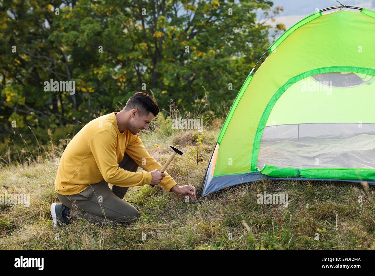 Man setting up camping tent on hill Stock Photo - Alamy