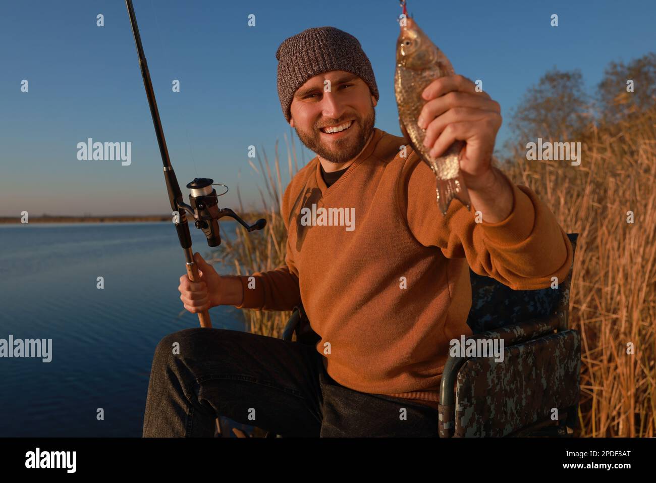 Fisherman with rod and caught fish at riverside Stock Photo - Alamy