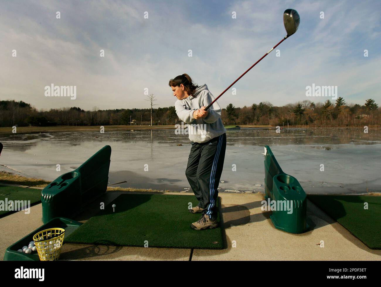 Karen Day of Stoneham, Mass. hits golf balls over an icy pond at