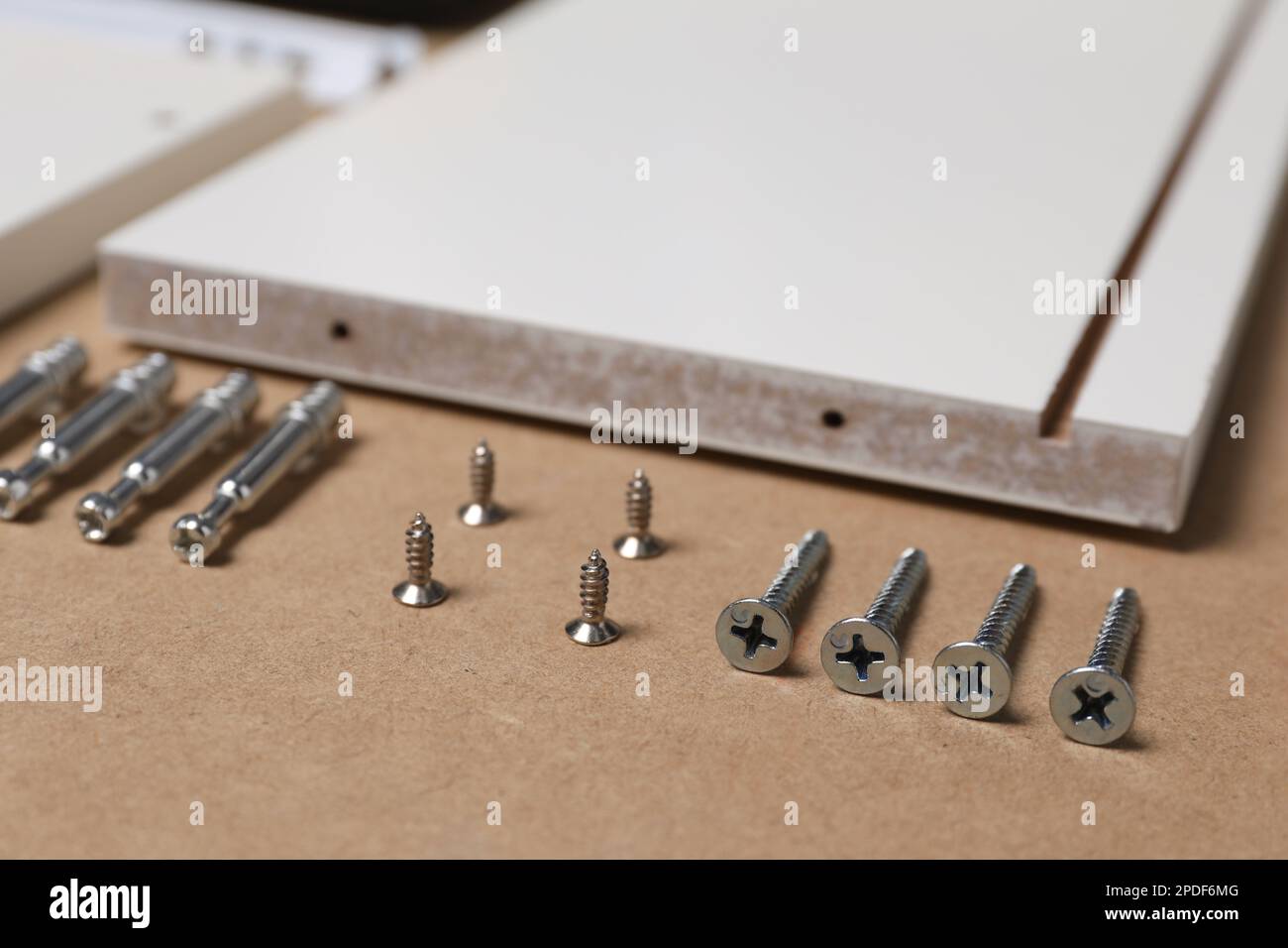 White furniture assembly parts and different metal fasteners on brown