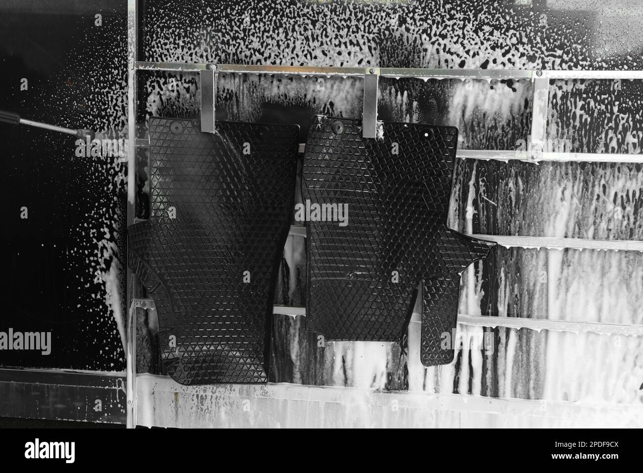 Cleaning auto mats with high pressure water jet at car wash Stock Photo