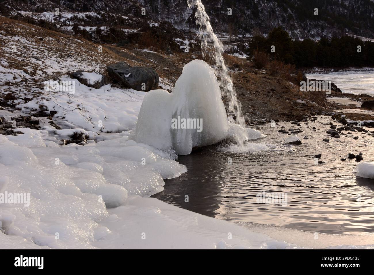 A narrow stream of water flows down onto an ice block into a small