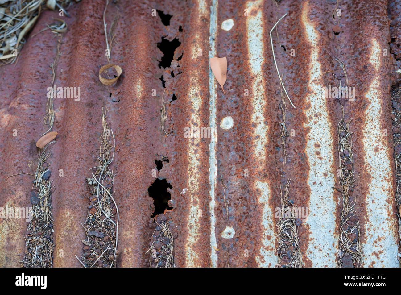Close up view of an old rusted corrugated iron water tank with holes in