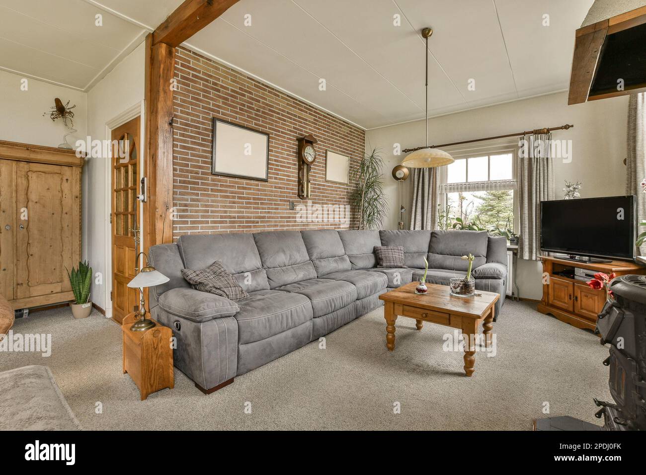a living room with couches and a television set in the middle of the room, there is a brick wall that has been Stock Photo