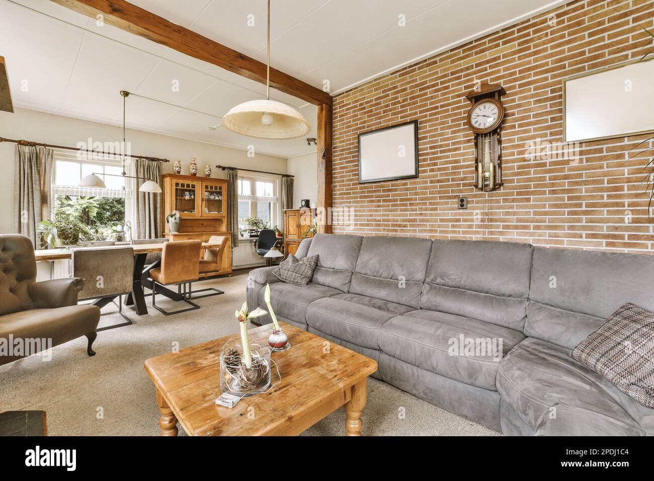 a living room with couch, coffee table, and tv on the wall in front of the sofa is made out of red brick Stock Photo