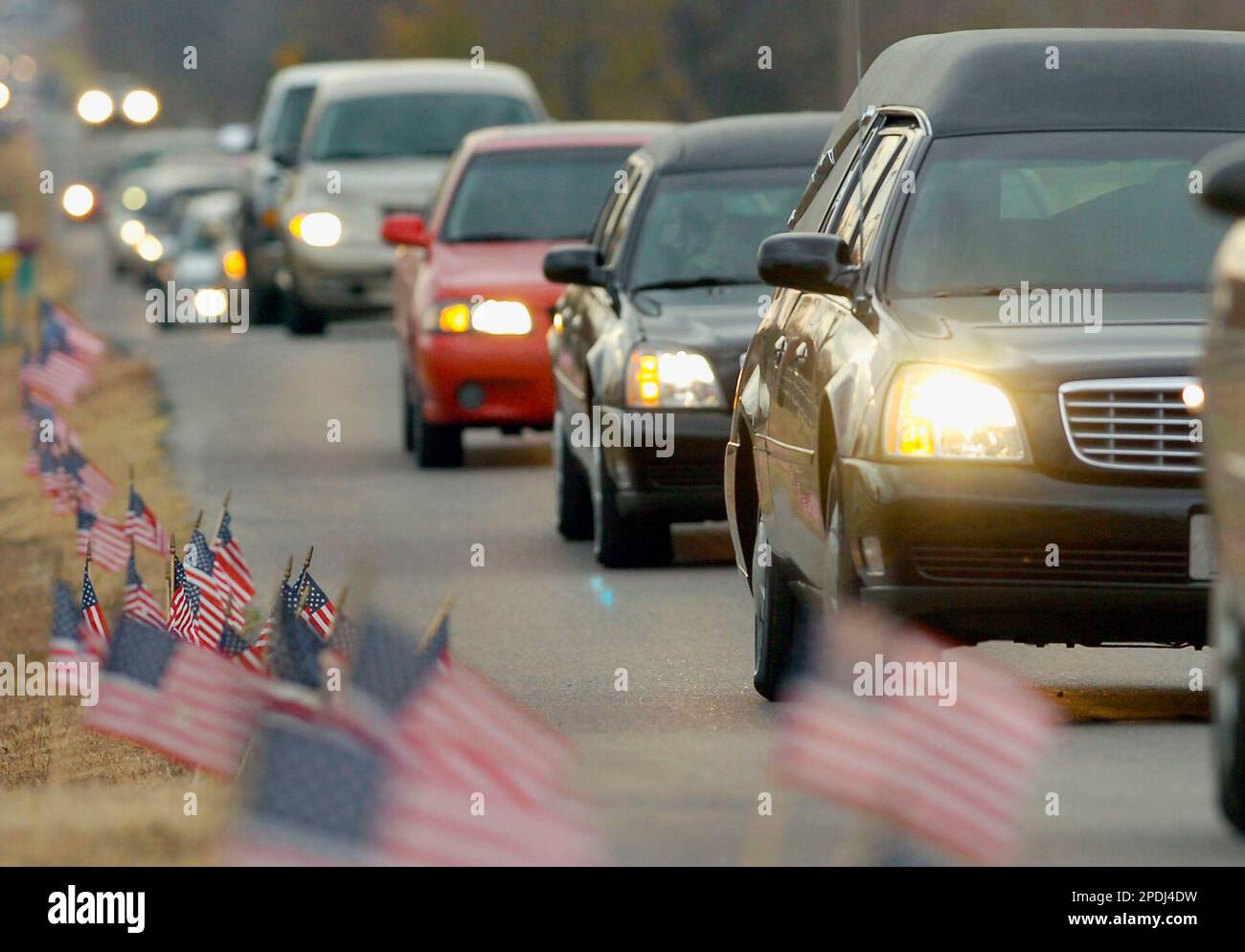 The hearse and procession makes its way down flaglined Cemetary Road