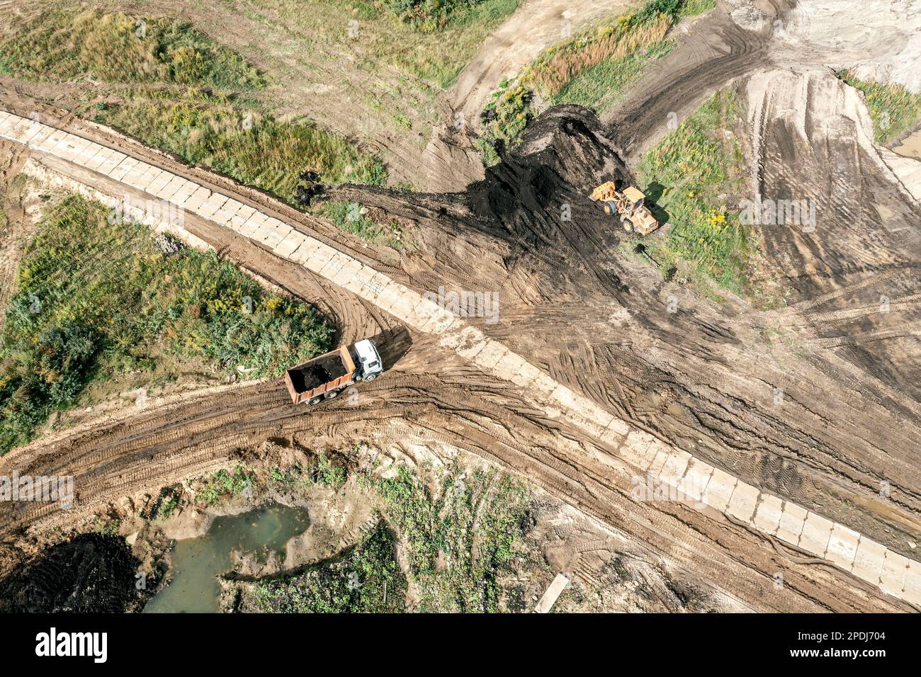 earthmoving at construction site. aerial view of dump truck and digger in the process of working. Stock Photo