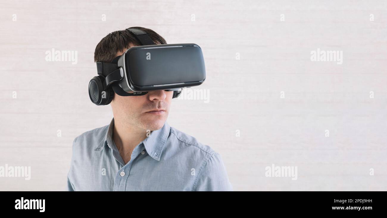 Astonished caucasian male in blue t-shirt, using oculus rift headset, experiencing virtual reality while playing video game, looking joyful, white wal Stock Photo